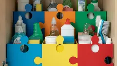 Barevné úložné boxy ve tvaru puzzle na čisticí prostředky v organizované skříňce.