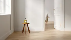 Minimalistický interiér s dřevěnou stoličkou a lahví v bílé místnosti