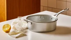 Nerezový hrnec s pokličkou na kuchyňské lince vedle citronu, mléka a soli.